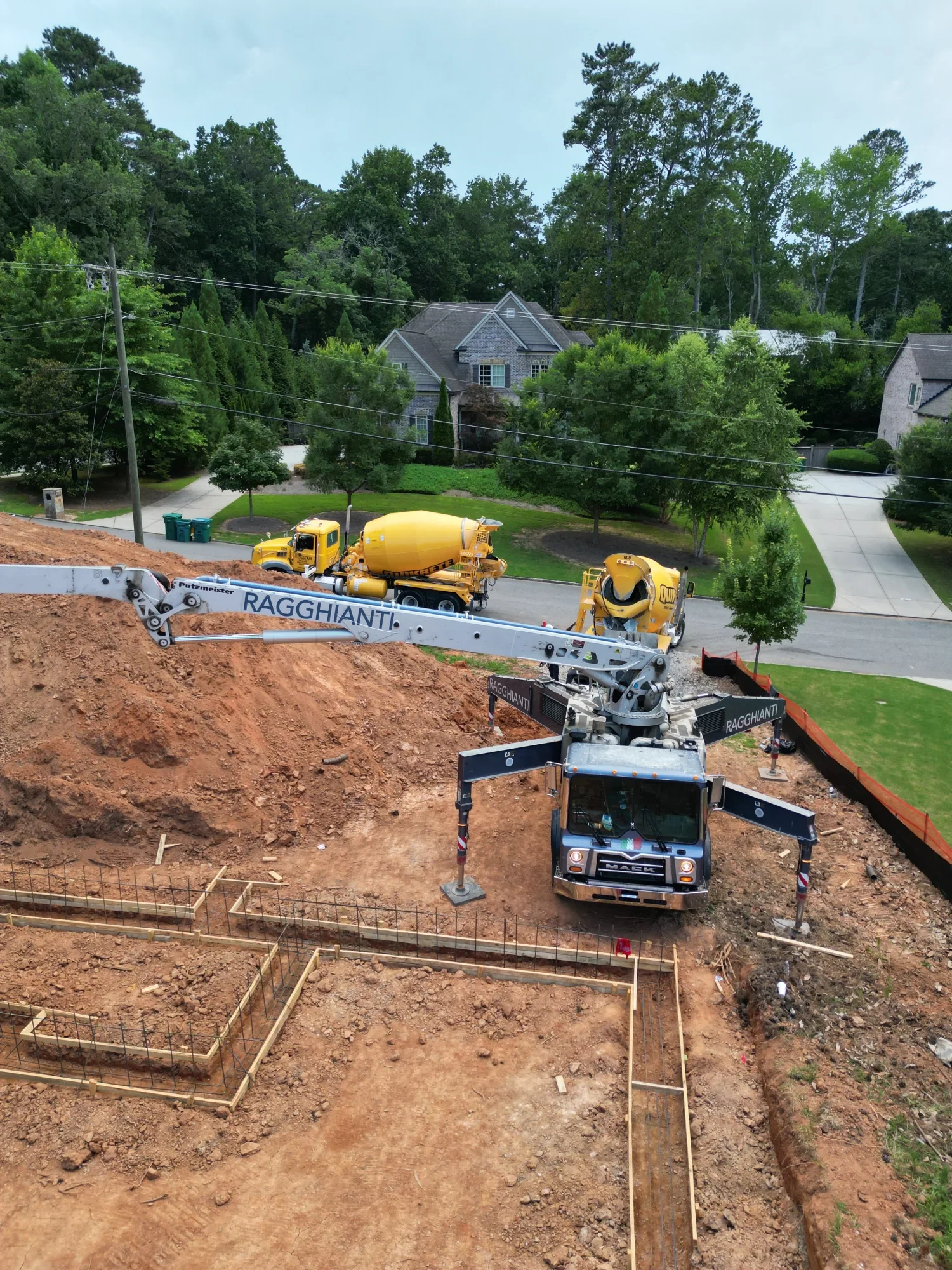 Concrete pump truck positioned beside excavated custom home footings